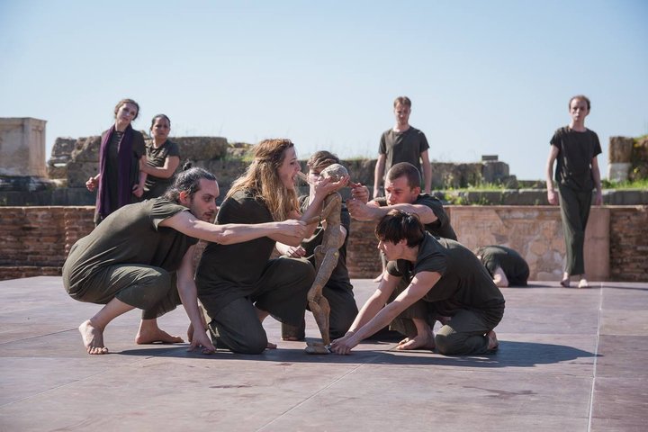 group of MA Theatre Lab students perform The Trojan Women with a puppet on on the stage of an ancient Greek amphitheatre