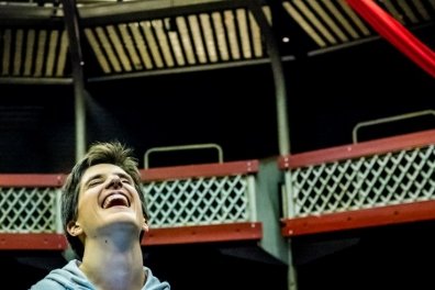 Male actor looks upwards laughing in a theatre audtorium