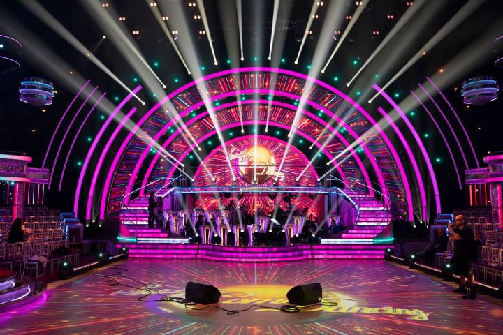 The stage set in a TV studio for Strictly Come Dancing with bright pink & red lights shining across the stage, back wall and out towards the audience